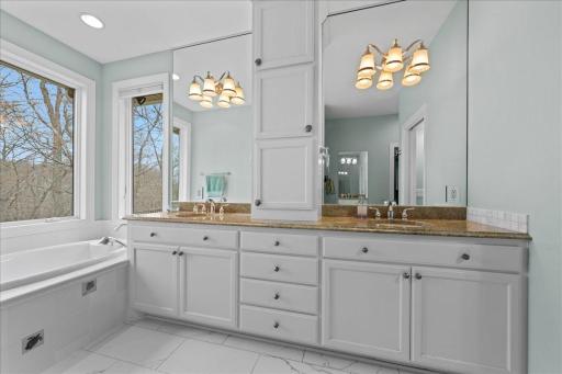 Primary bathroom with natural lighting and light fixtures over double vanities.