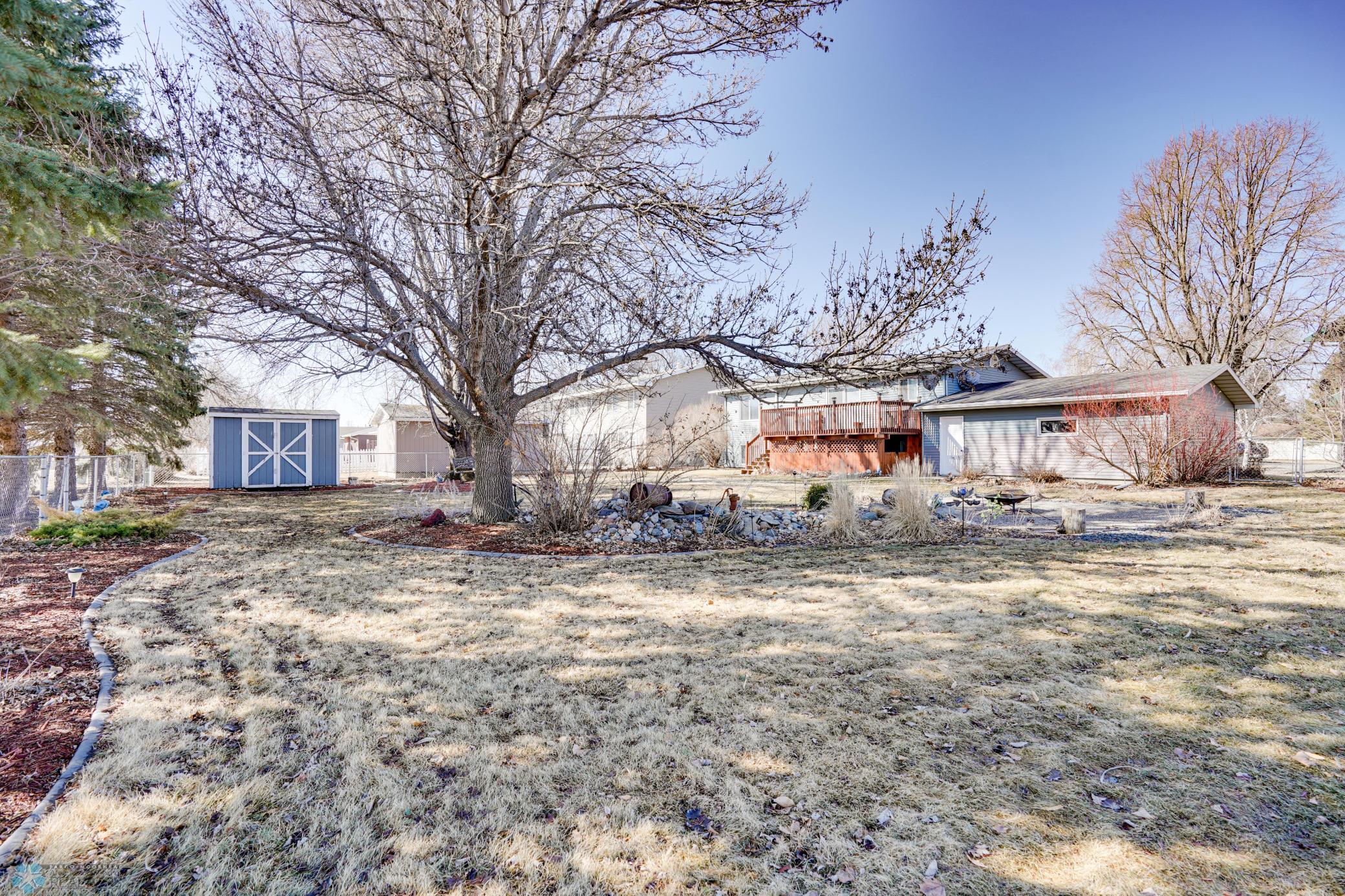 Spacious yard with mature trees, fire pit, storage shed, landscaping