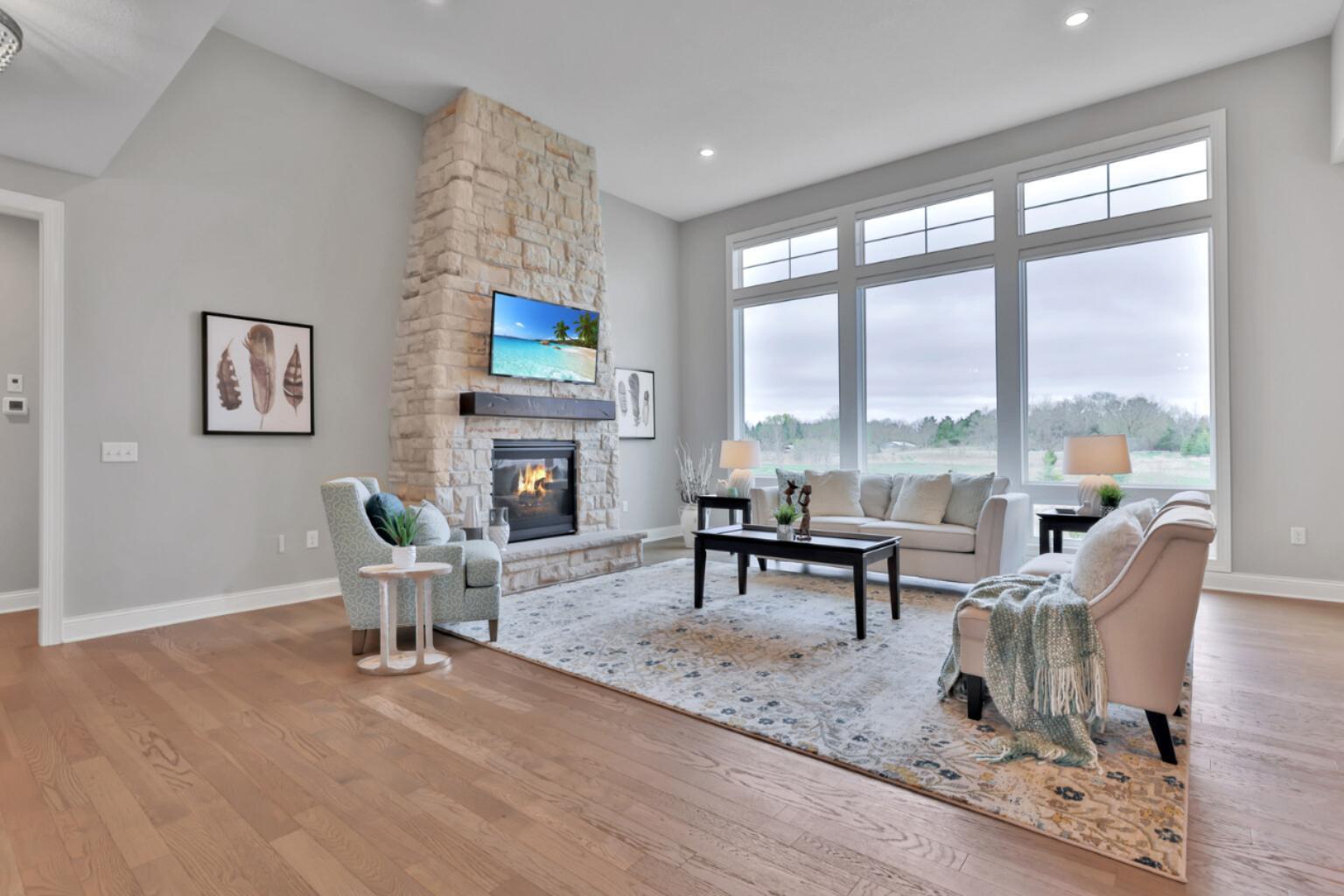 Extra high ceilings in the living room, floor to ceiling windows and stone fireplace makes this room so inviting