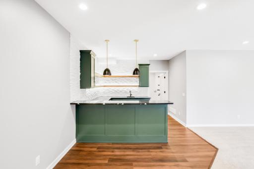 The large wet bar features separate wine and beverage fridges, open shelving and quartz tops.