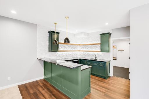 The large wet bar features separate wine and beverage fridges, open shelving and quartz tops.