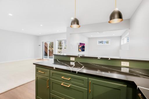 The large wet bar features separate wine and beverage fridges, open shelving and quartz tops.