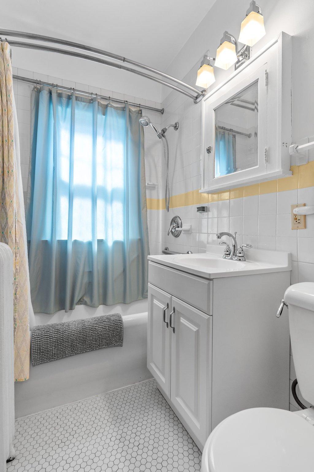 Tiled floors and walls. A shower and a deep tub are perfect for bathing.