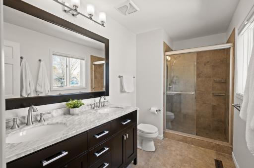 Private primary bath with granite top double vanity and tiled shower