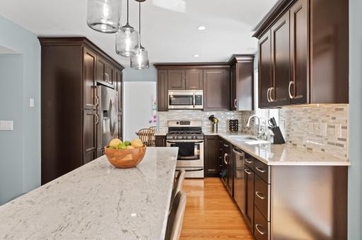 This kitchen sparkles! Featuring gleaming cherry cabinetry, granite countertops, kitchen island, stainless steel appliances and tiled backsplash, recessed lights and beautiful glass pendants.