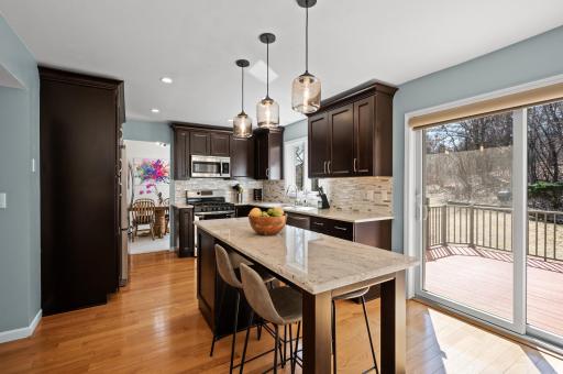 This kitchen sparkles! Gleaming cherry cabinetry, granite countertops, kitchen island, stainless steel appliances and tiled backsplash.