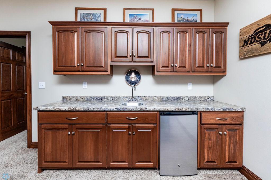 Wet bar offers sink, mini fridge space, cabinetry.