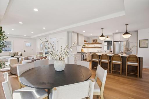 The main level boasts a designer kitchen with a large quartz island, gas range, custom hood, tile backsplash, and open flow into a formal dining space.