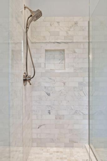 Tile and glass shower with niche in primary bedroom.