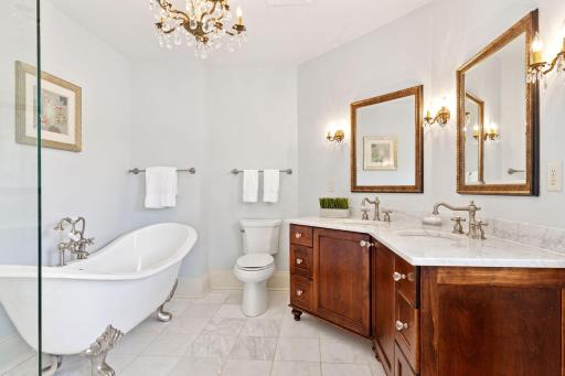 The private primary bathroom offers a spa-like experience, complete with high-end finishes, large double sink vanity, clawfoot bathtub, tile shower and tile flooring.