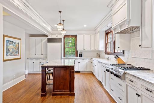 At the heart of the kitchen is a gorgeous central island with a contrasting base, lovely pendant chandeliers hang above, complemented by recessed lighting. Tons of cabinets and counter space!
