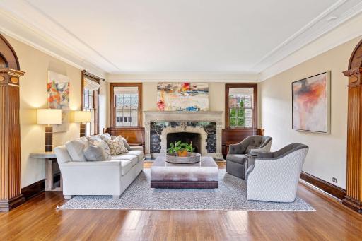 The warm living room boasts 9-foot ceilings and crown molding, exuding classic elegance. Double-hung wood windows with dark frames and trim throughout the main level add charm and functionality!