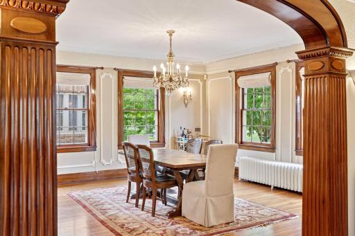 An elegant formal dining room, beautifully framed with intricate wall molding, decorative crown molding, and expansive windows. This stunning space seamlessly connects to the updated kitchen.