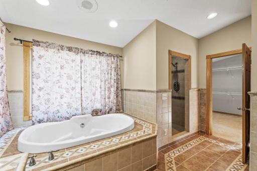 Primary bathroom featuring dual sinks, a tile shower, and a soaking tub.
