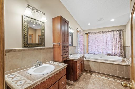 Primary bathroom featuring dual sinks, a tile shower, and a soaking tub.
