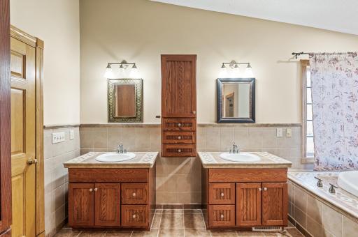 Primary bathroom featuring dual sinks, a tile shower, and a soaking tub.