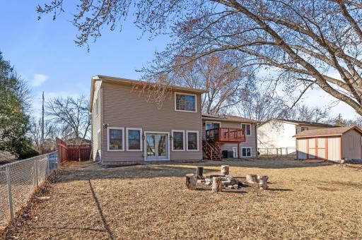 Spacious fenced in backyard with a fire pit and shed.