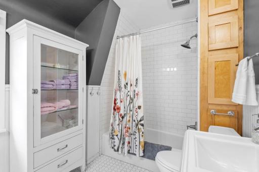 Functional and elegant, bathroom includes a full tub, new toilet, and tasteful heated tile floorsâall under a unique sloped ceiling.