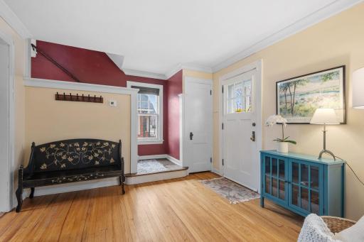The welcoming front entry offers a mix of character and function with hardwood floors, a bench nook, and charming details like the bold red accent wall and paneled door.