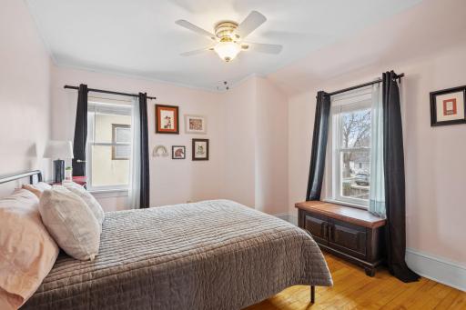 The second bedroom is filled with light and comfort, offering hardwood floors, two windows, and neutral tones perfect for guests, children, or flexible use.