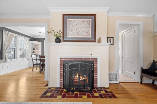 Warmth radiates from this elegant fireplace, complete with detailed millwork, a brick surround, and custom art aboveâanchoring the space with timeless charm.