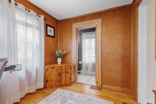 This versatile space with wood-paneled walls and built-in corner cabinetry can function as a home office, bonus room, or cozy den, with views into the hallway and bath.