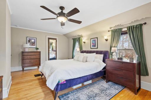 Another view of the primary bedroom reveals generous space, multiple windows, a ceiling fan, and plenty of room for a king-sized bed and additional furniture.