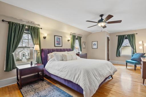 The spacious primary bedroom offers cove ceilings, natural light, rich hardwood floors, dual closets, a ceiling fanâcreating a relaxing and elegant space to unwind.