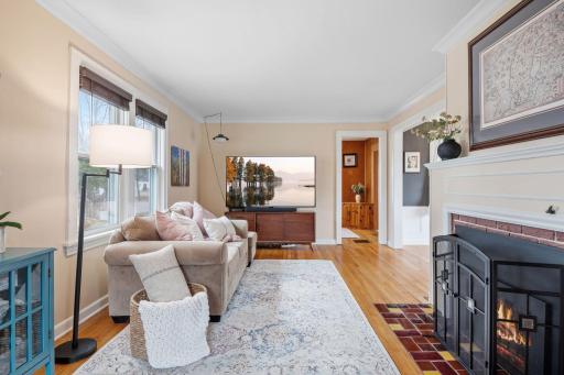 Step into a light-filled living room featuring gleaming hardwood floors, a cozy sofa nook, and a large TV framed by classic trim and warm, neutral tonesâideal for relaxing or entertaining.