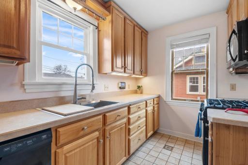 A large window over the sink brings in bright, natural light, highlighting the expansive countertop space, updated fixtures, and well-maintained wood cabinetry.