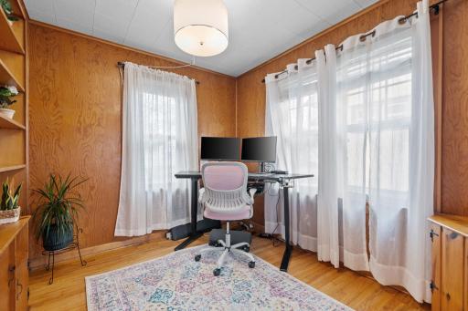 Bright and inviting, this main-level office/den is surrounded by natural light from multiple windows and enhanced with warm wood-paneled walls and hardwood flooringâideal for working from home or creative