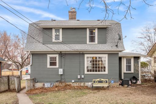 The rear of the home showcases durable siding, a large picture window, and a quaint backyard with space for entertaining, gardening, or relaxation.