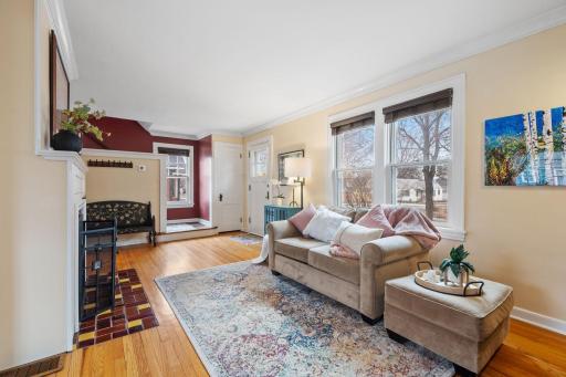 This inviting living area is filled with natural light from multiple windows and highlighted by a bold accent wall, cozy fireplace, and open sightlines to the entryway.