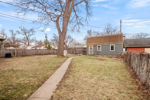 This spacious fenced-in backyard offers plenty of room for outdoor activities, gardening, or entertaining, with a charming walkway leading to the oversized garage with loft storage.