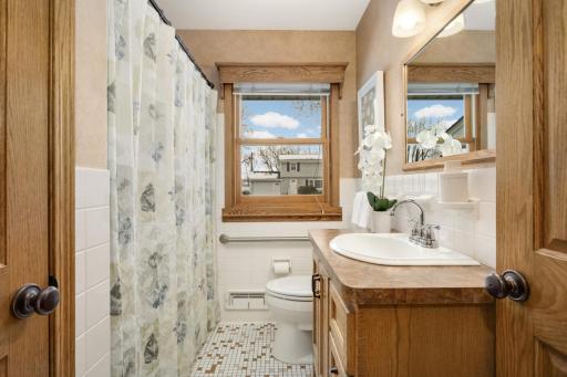 Main Floor Full bathroom with tiled floors and walls. Handicap accessible bathtub with grab bars.