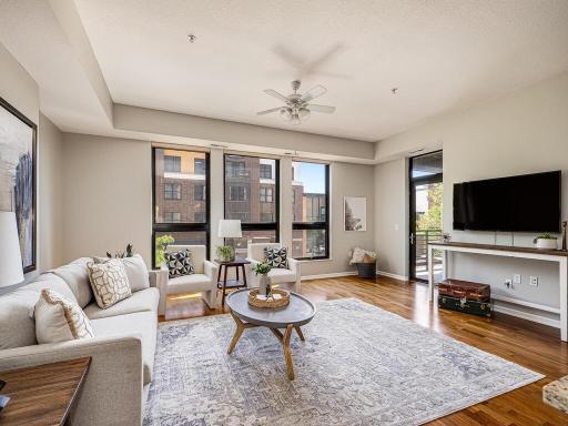 Unit 215's living room features floor-to-ceiling windows and wood floors. This south facing home is filled with sunlight throughout.