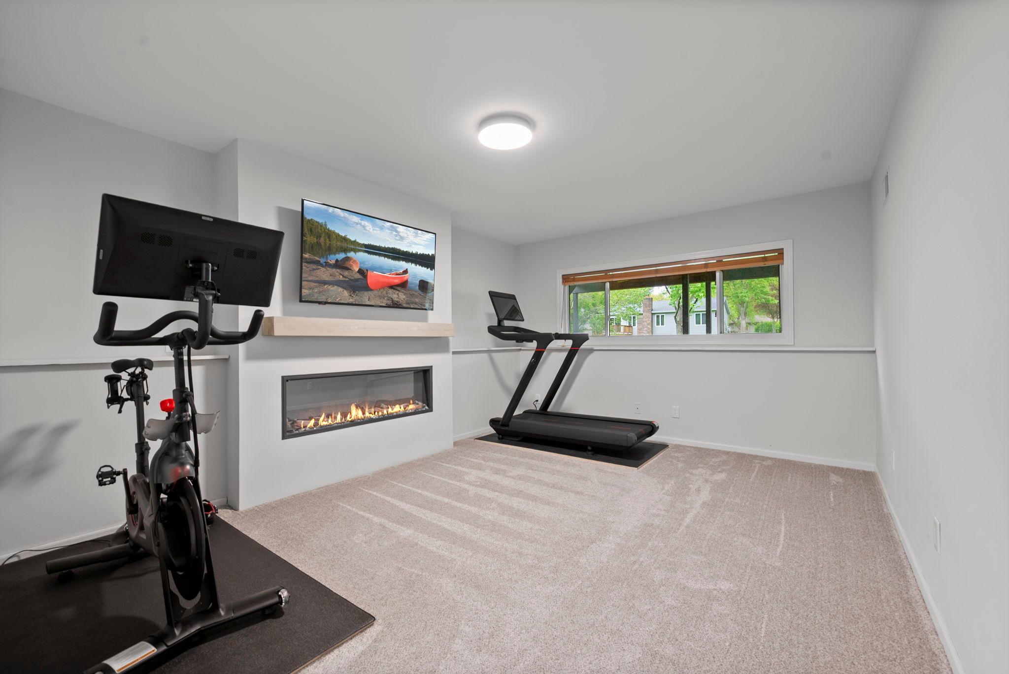 Lower level family room has new carpet and electric fireplace. Seller's use for their Peloton equipment/workout area.