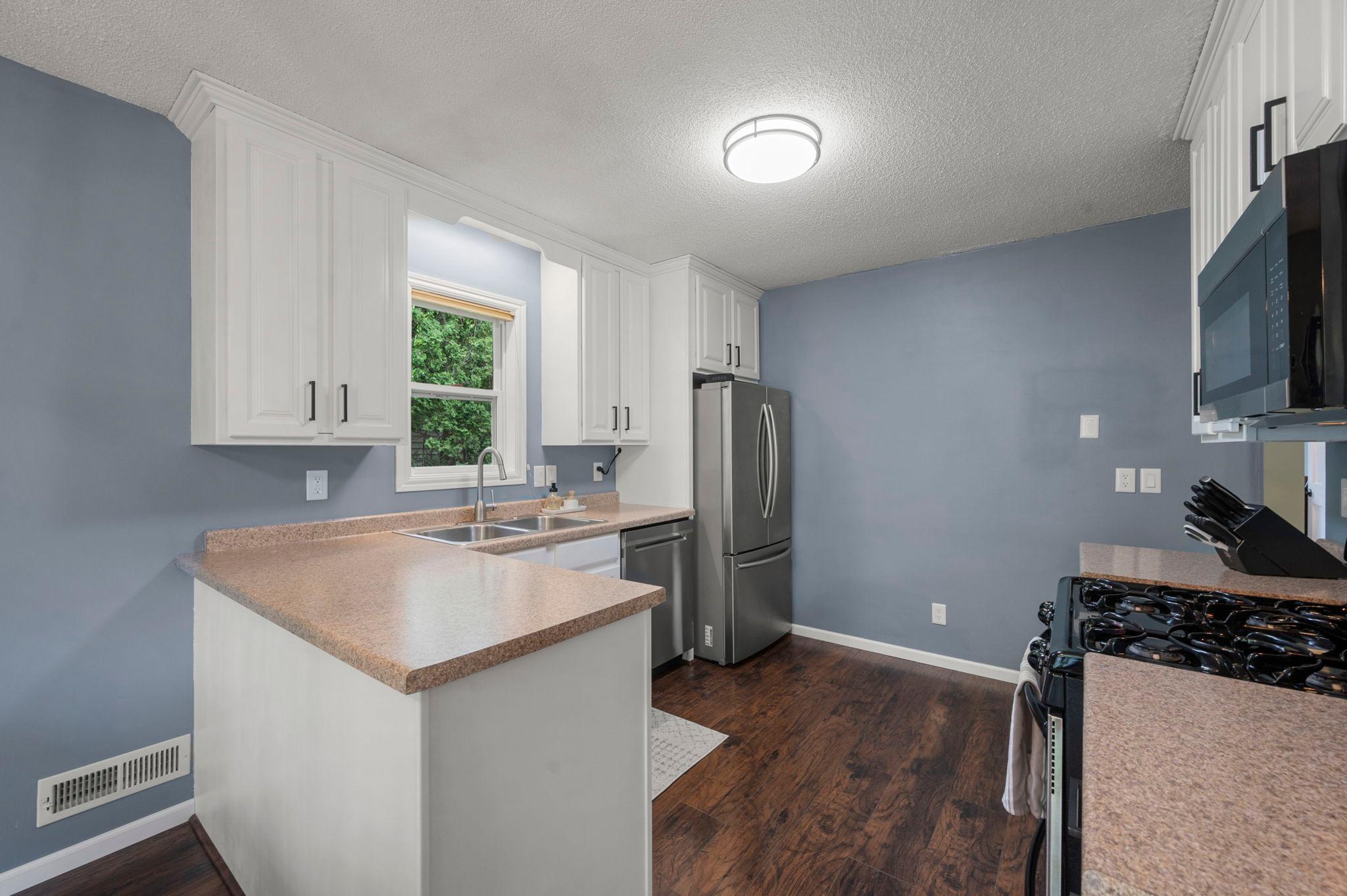 Kitchen has white painted cabinets, stainless appliances, 42" upper cabinets, new hardware, refrigerator, dishwasher, gas stove, new light, new GFCI, built in microwave, and exhaust to outside.