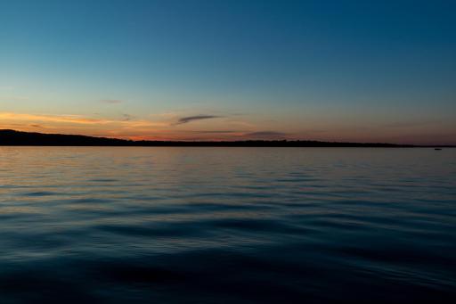Peaceful lake view at dusk with soft sunset horizon.