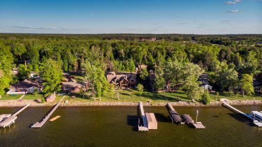 Aerial view of custom estate with dual docks and manicured shoreline.