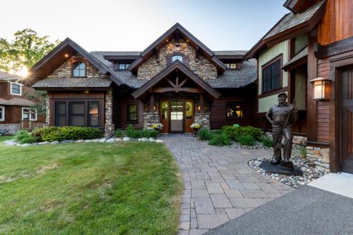 Grand front entrance with custom stonework, timber accents, and professional landscaping for a welcoming first impression.