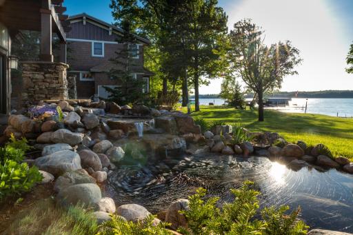 Professionally landscaped stream with rock garden and lake backdrop.