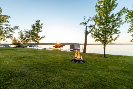Lakeside firepit with open green space and a stunning sunset view—perfect for evening gatherings by the water.