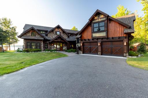 Stunning custom home with rich wood and stone exterior, oversized 3-car garage, and grand covered entry.