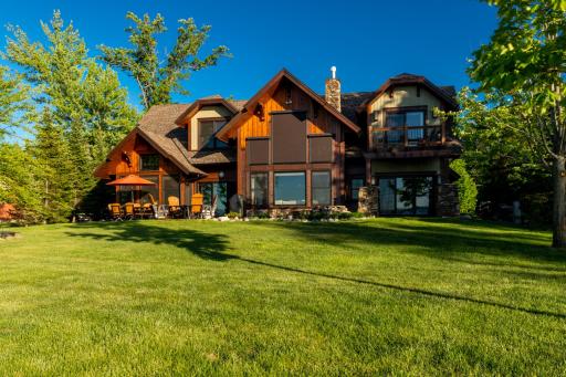 Rear exterior showcasing lush lawn, large deck, and timeless architectural design.