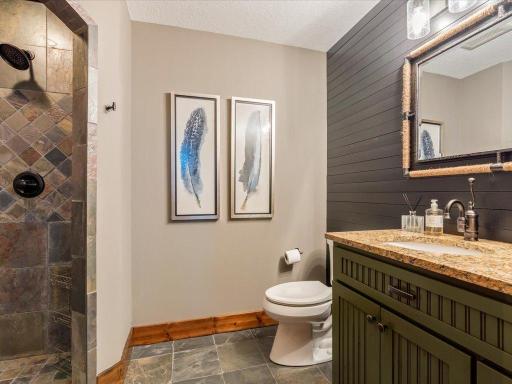 Half bath with textured feature wall, framed mirror, and warm wood accents.