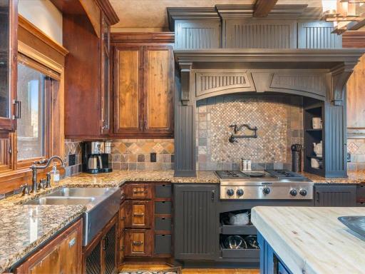Gourmet kitchen with custom vent hood, gas range, and richly detailed wood cabinetry.
