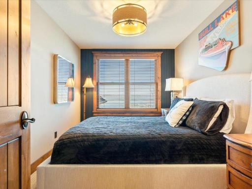 Guest bedroom with designer lighting, large windows, and calming color palette.