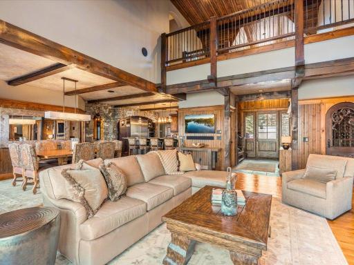 Expansive open-concept main level with soaring ceilings, exposed beams, and seamless flow from living to dining and kitchen areas.
