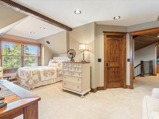 Upper-level bedroom with tray ceiling, exposed beam, and serene lake views.